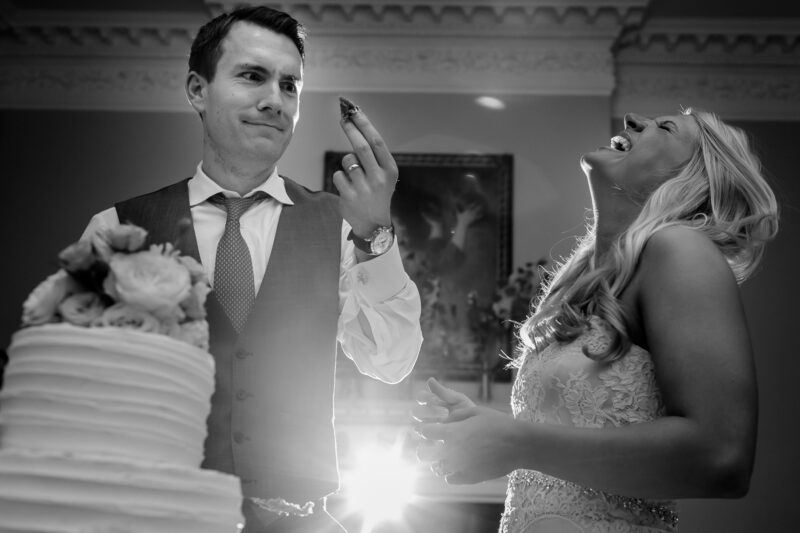 Bridebook.co.uk- bride and groom eating their wedding cake and laughing