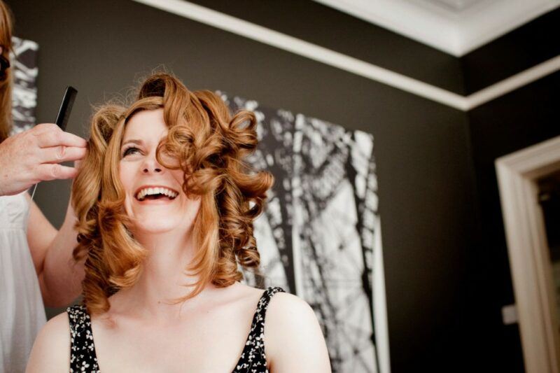 Bridebook.co.uk- bride laughing while having her hair done