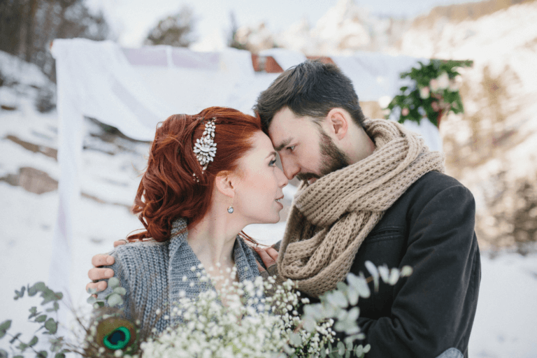 Bride and groom tying the knot in a winter wedding wearing a warm cardigan and scarf