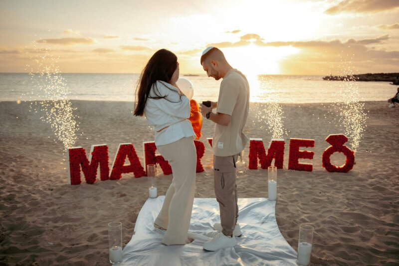 Couple on a beach with a Marry Me sign