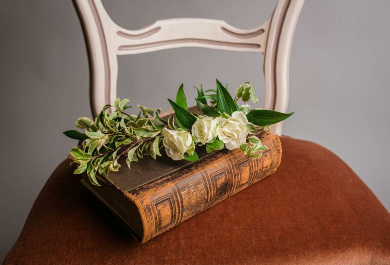 Old book on a chair with white roses