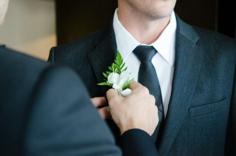Someone putting a boutonnière on a groom