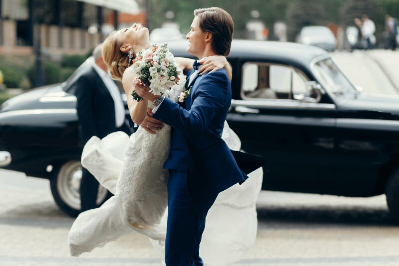Bride jumping into groom's arms, coming out from a car