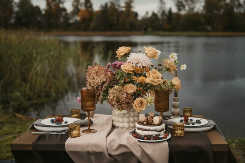 Flowers and cake on a table by a lake