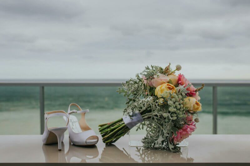 Bouquet et chaussures de mariée au bord de la mer